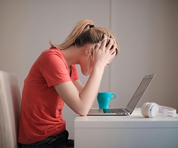 A sad person in front of a computer